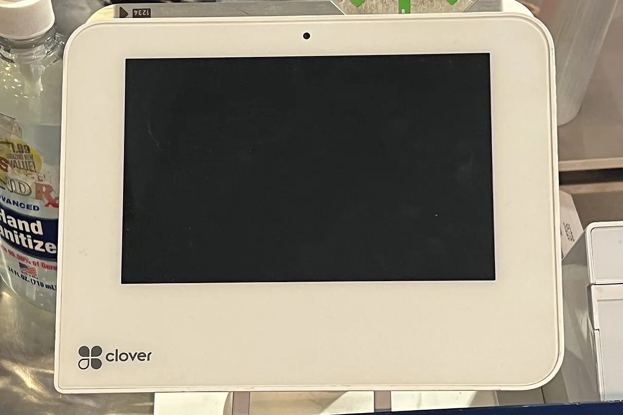 A card payment terminal on a shop counter, its screen dark