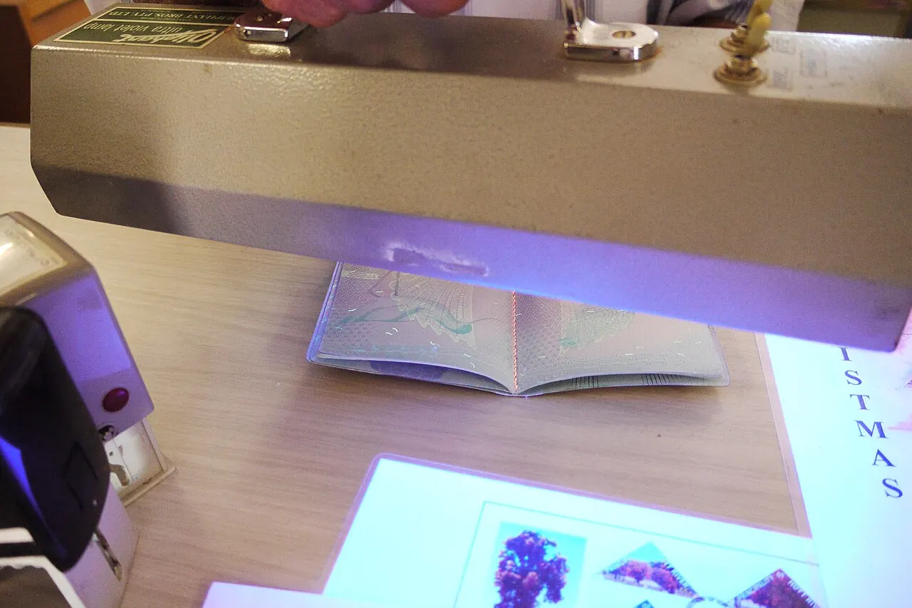 A passport held open under an ultraviolet lamp